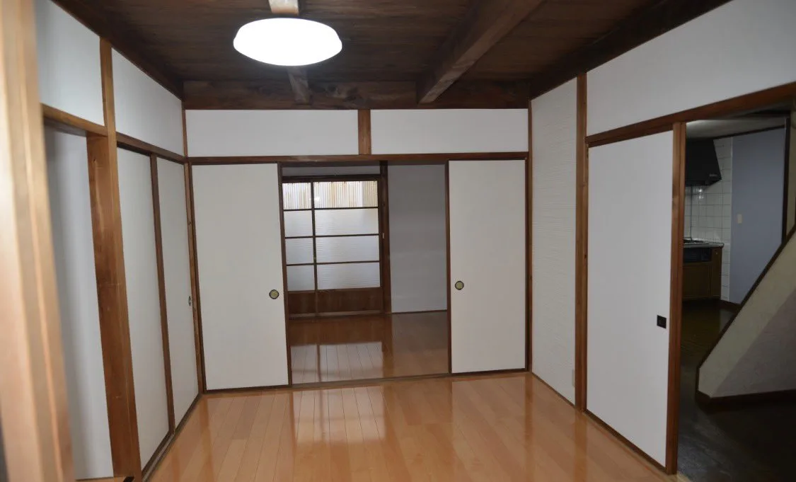 リフォーム後: 同じ部屋がフローリングと白い壁・襖に生まれ変わった様子